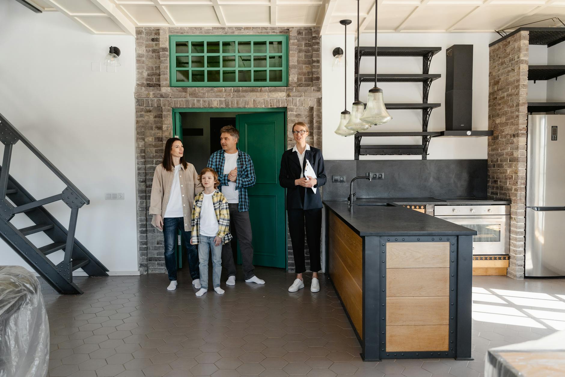 A family with a realtor viewing a modern industrial-style kitchen in a new home.