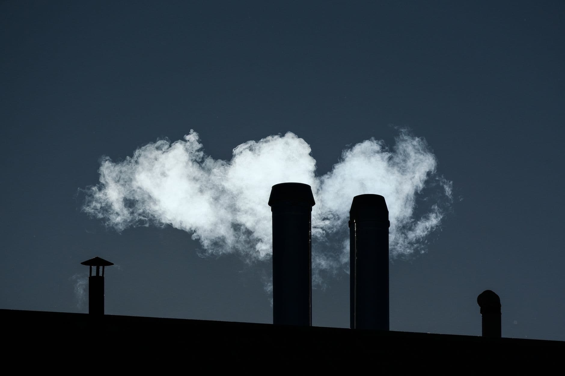 Silhouetted chimneys emit smoke into the sky creating an industrial scene.