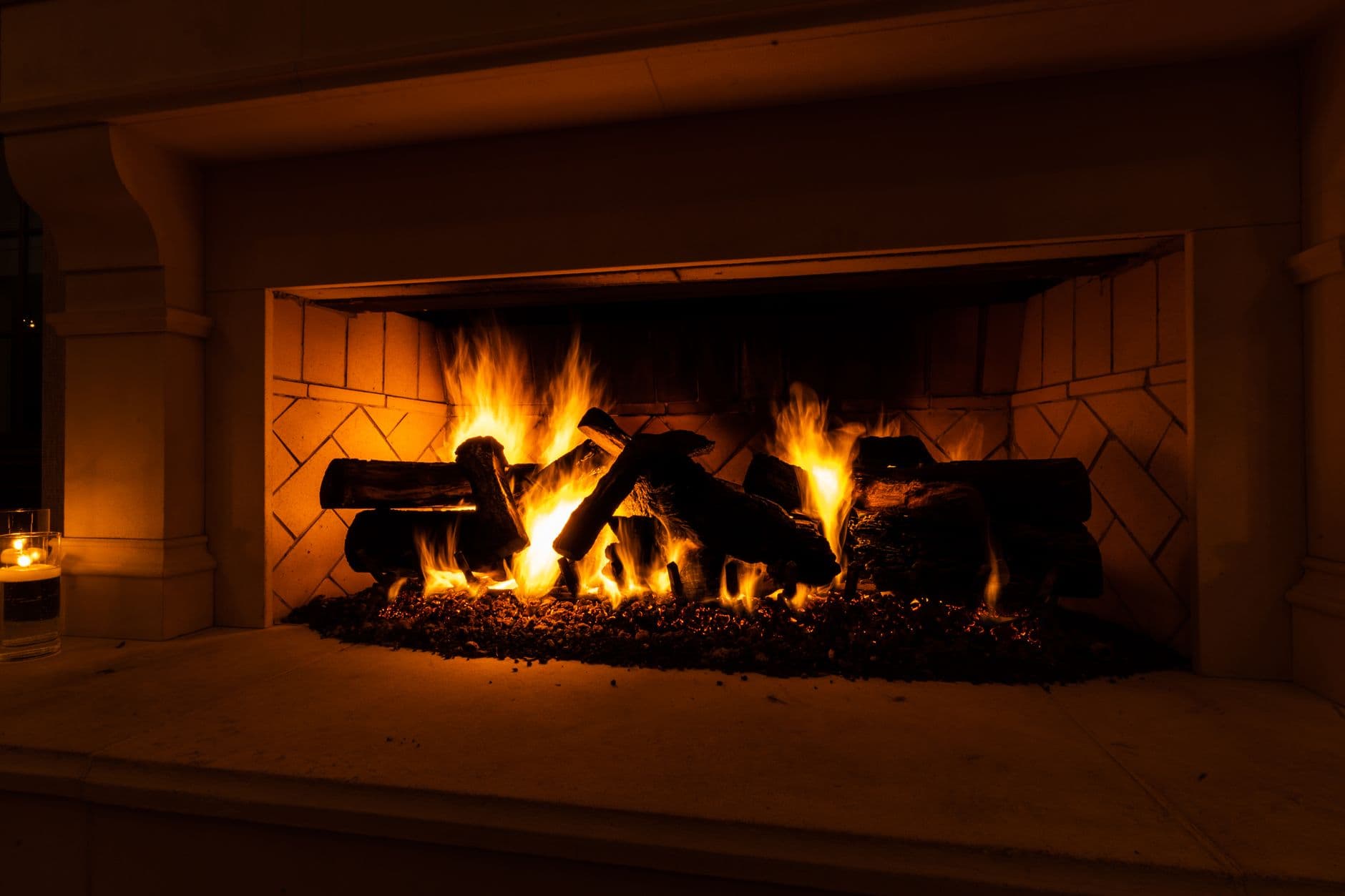 A warm and inviting close-up of a fireplace with glowing flames and firewood.